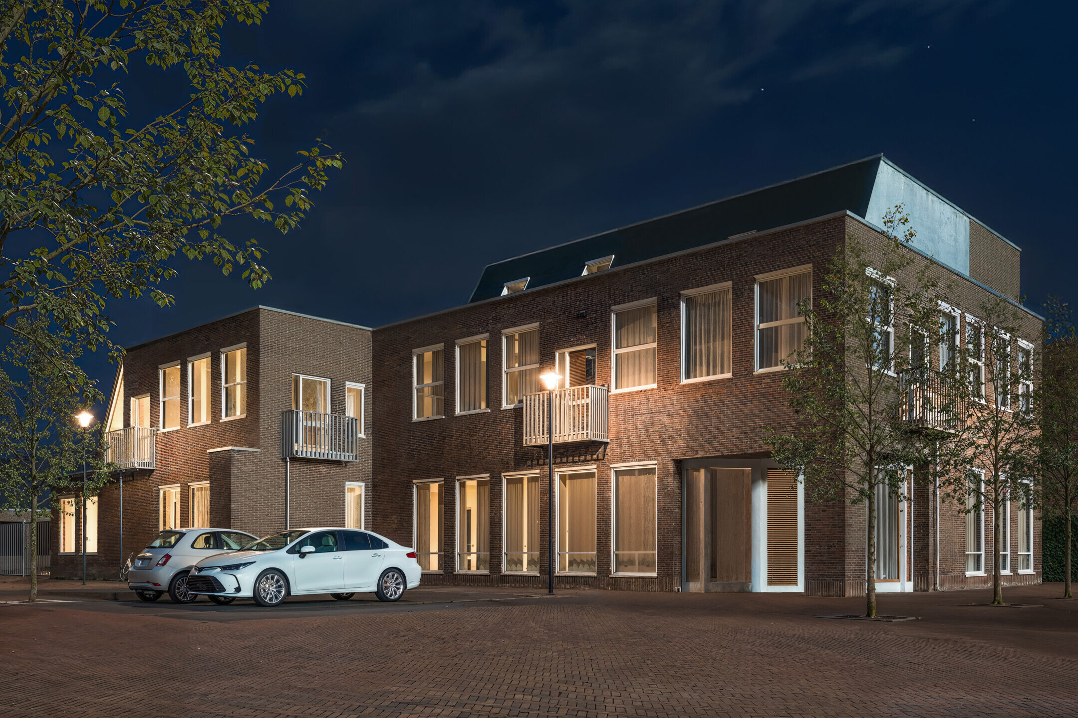 Artist impression van het buitenaanzicht van een AZC met moderne gevels, groenvoorziening en toegankelijke inrichting van de buitenruimte