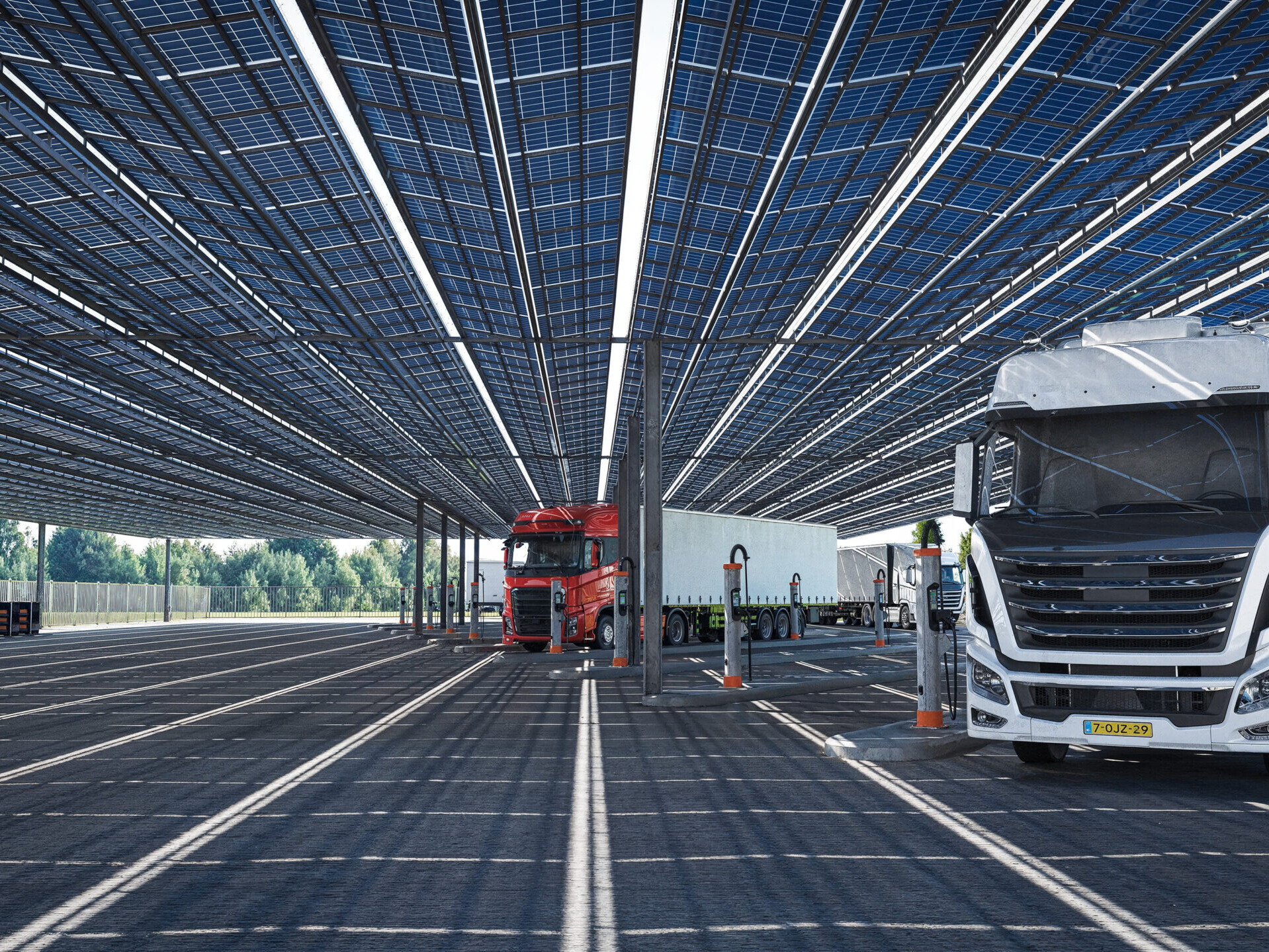 Artist impression van een duurzaam truck laadstation met zonnedak en meerdere elektrische vrachtwagens aan laadpunten